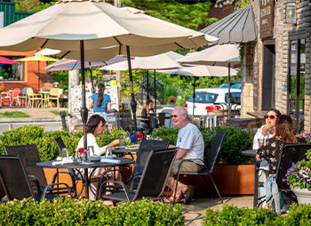 people sitting on a patio under an umbrella